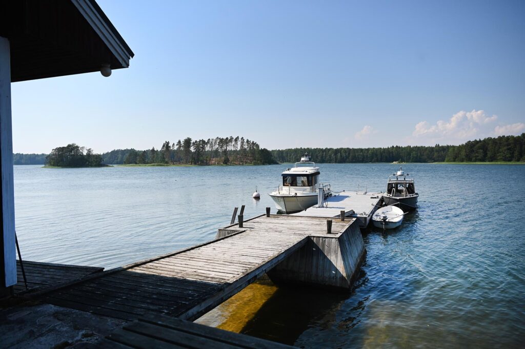 Tre båtar vid en brygga med skärgården i bakgrunden.